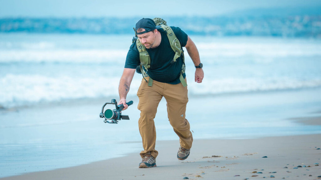 Jeven Dovey running on beach filming with a camera